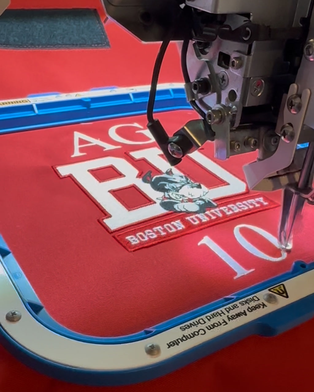 Custom embroidery being applied to a Boston University captains chair.