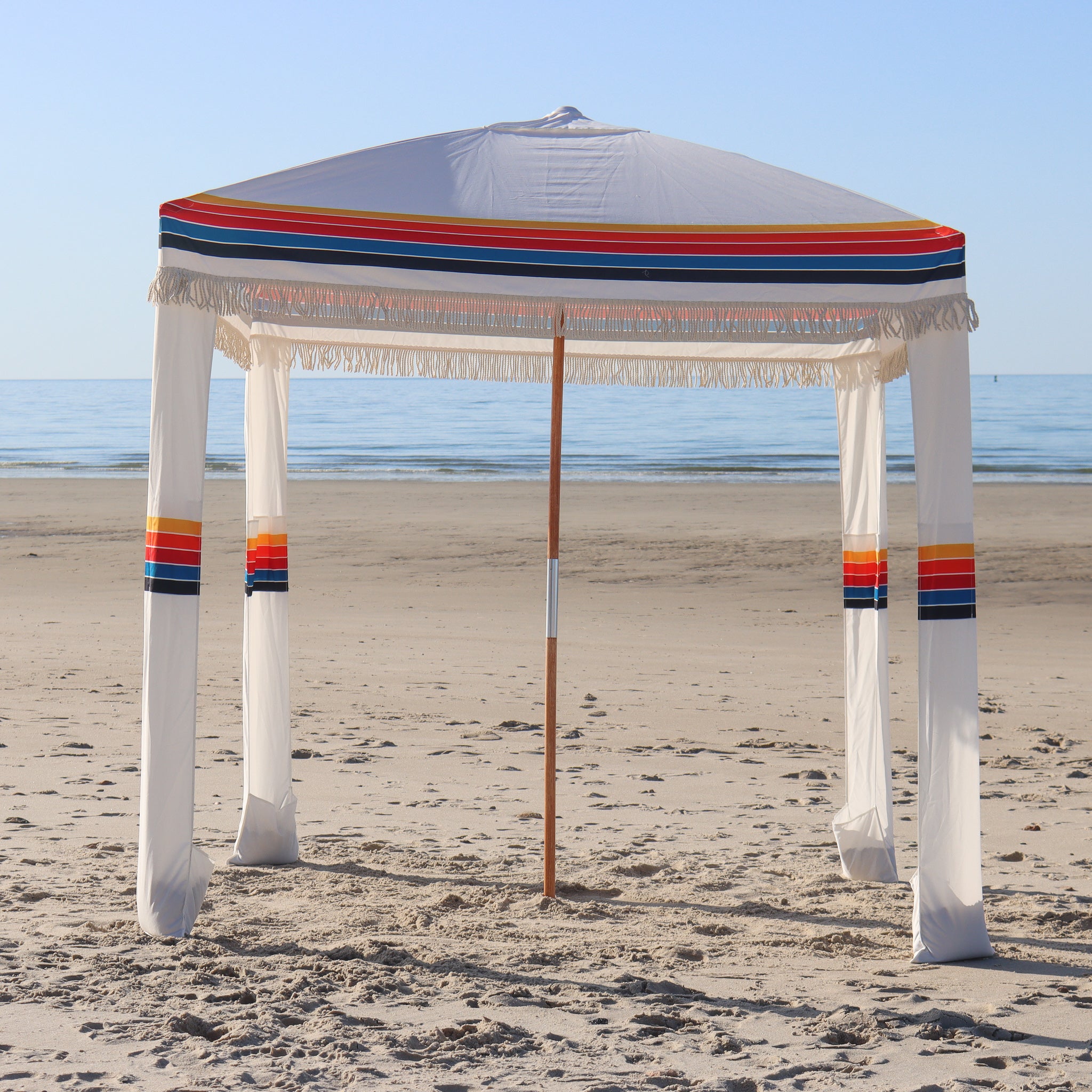 white beach cabana with retro multicolor rainbow stripes on the beach