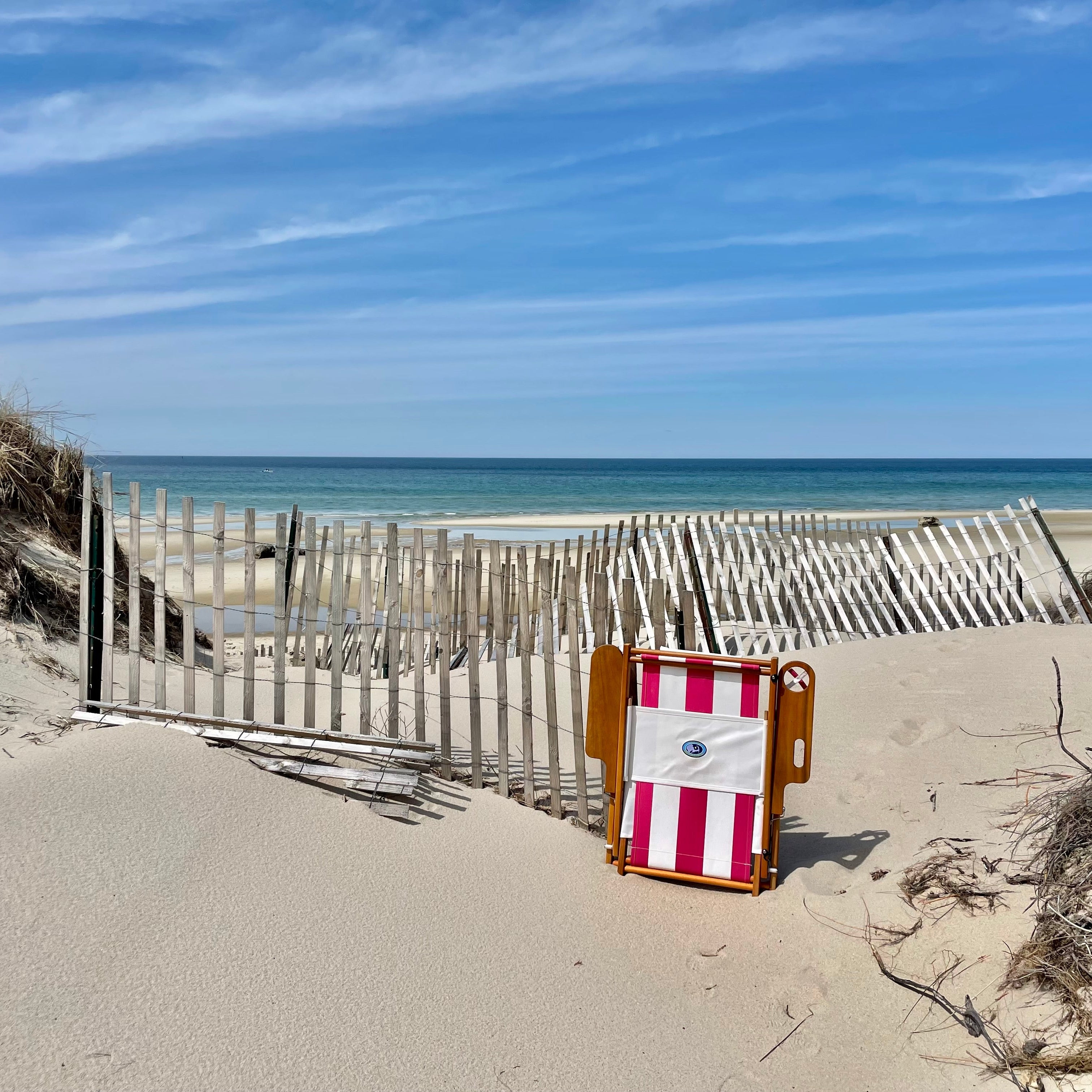 Pink and white striped beach chair on cape cod beach amidst dunes