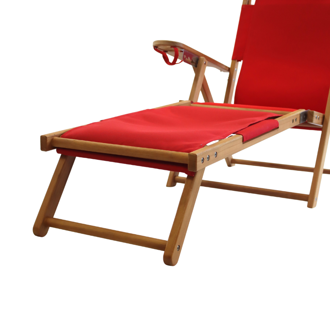 Red cushioned lounge chair with wooden frame and footrest attachment