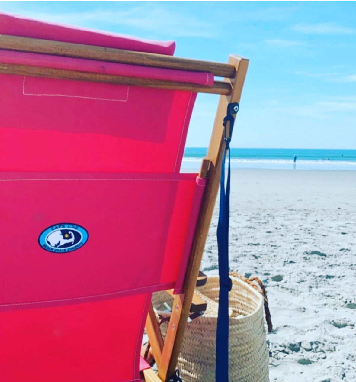 A beautiful pink beach chair with a tote bag on the beach.