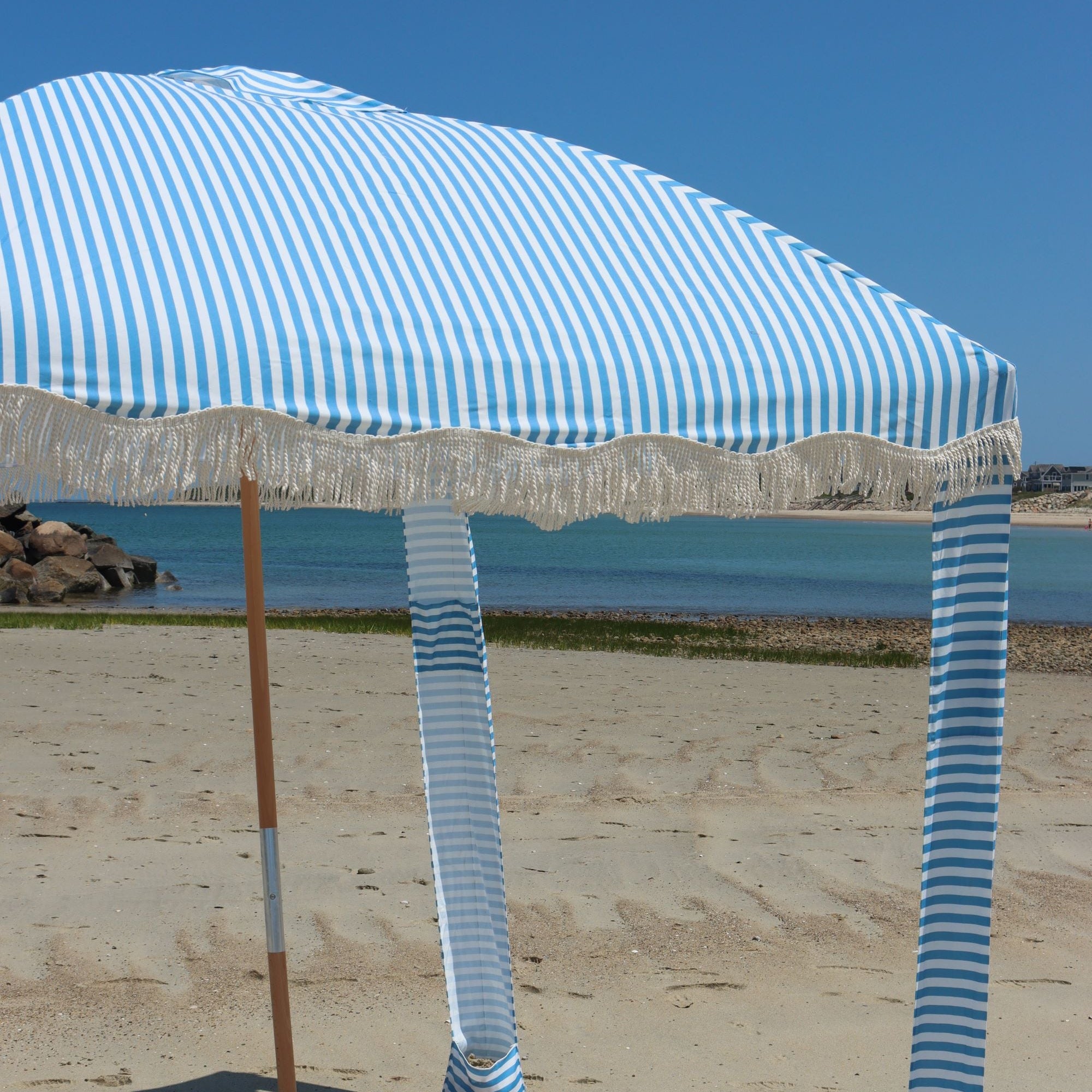 East to set up light blue and white striped beach cabana with tassels on cape cod beach