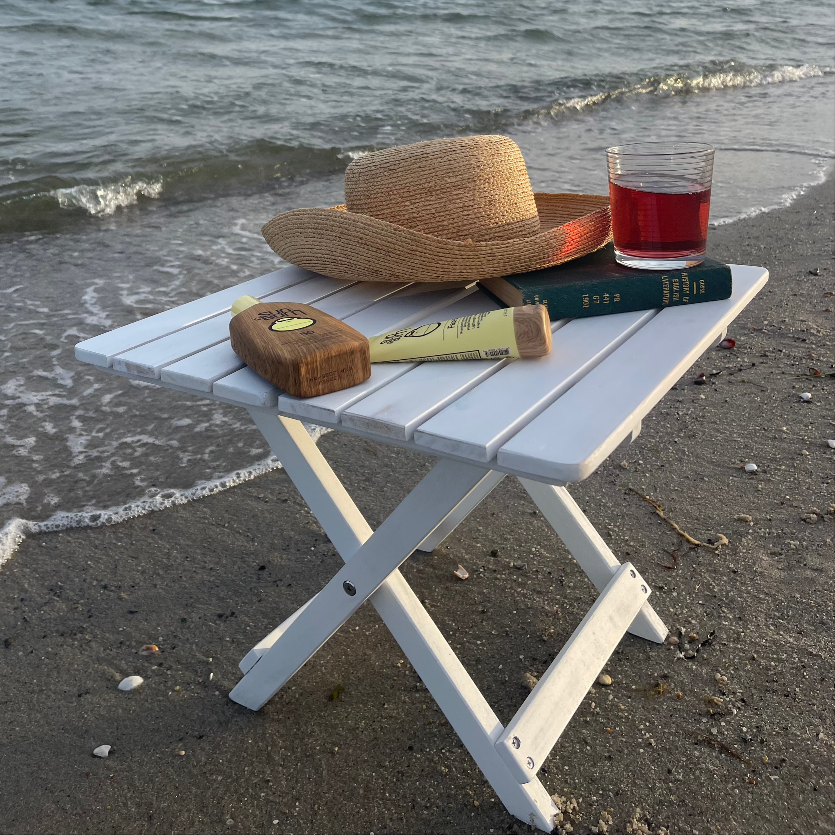Coastal White Beach Table on Beach with Beach Hat and Suncreen