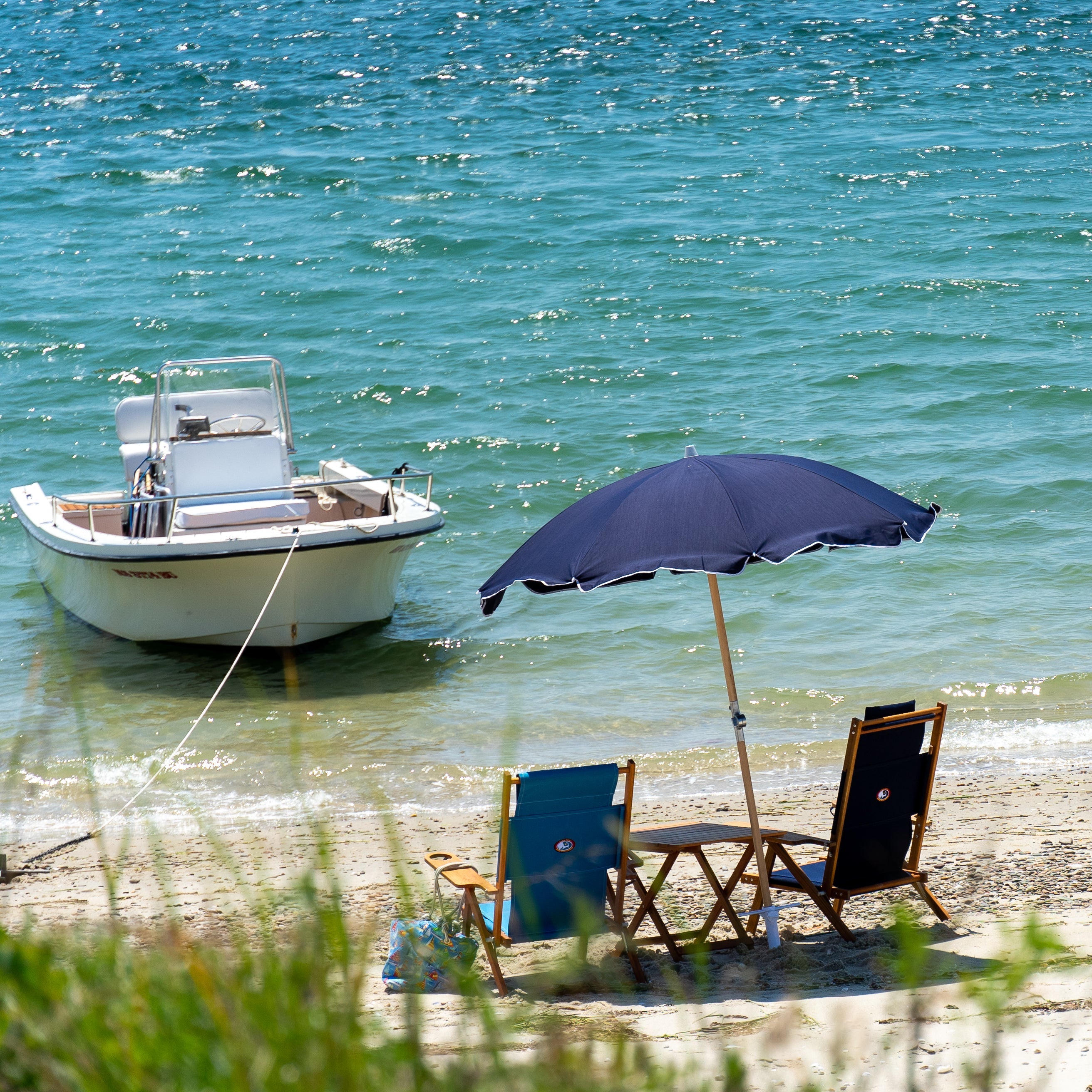 Premium navy beach umbrella on beach with boat