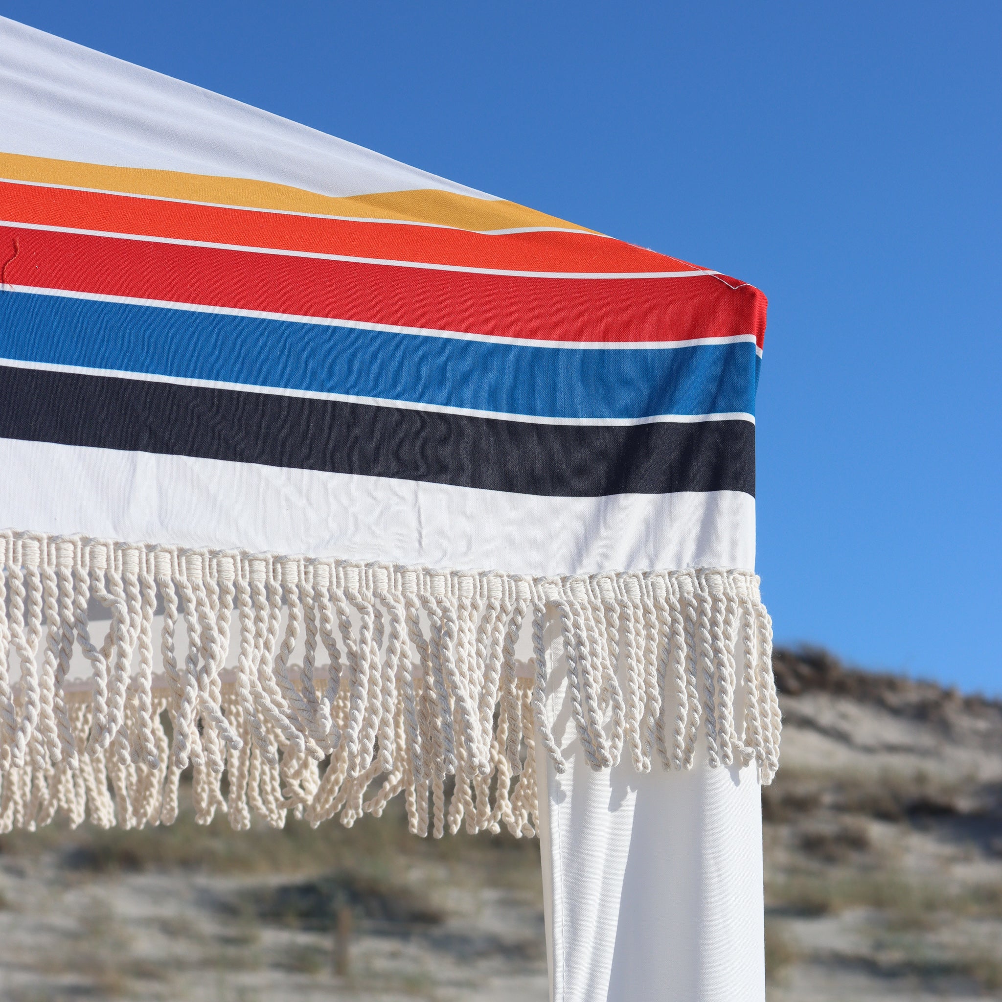 white beach cabana with stripes and cotton tassels