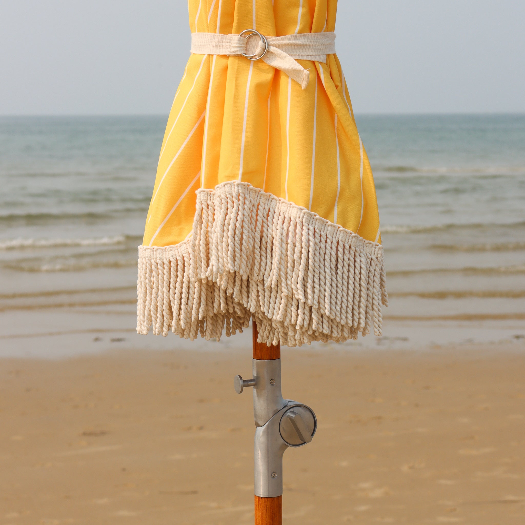 Yellow pinstripe beach umbrella with cotton fringe and tilt mechanism