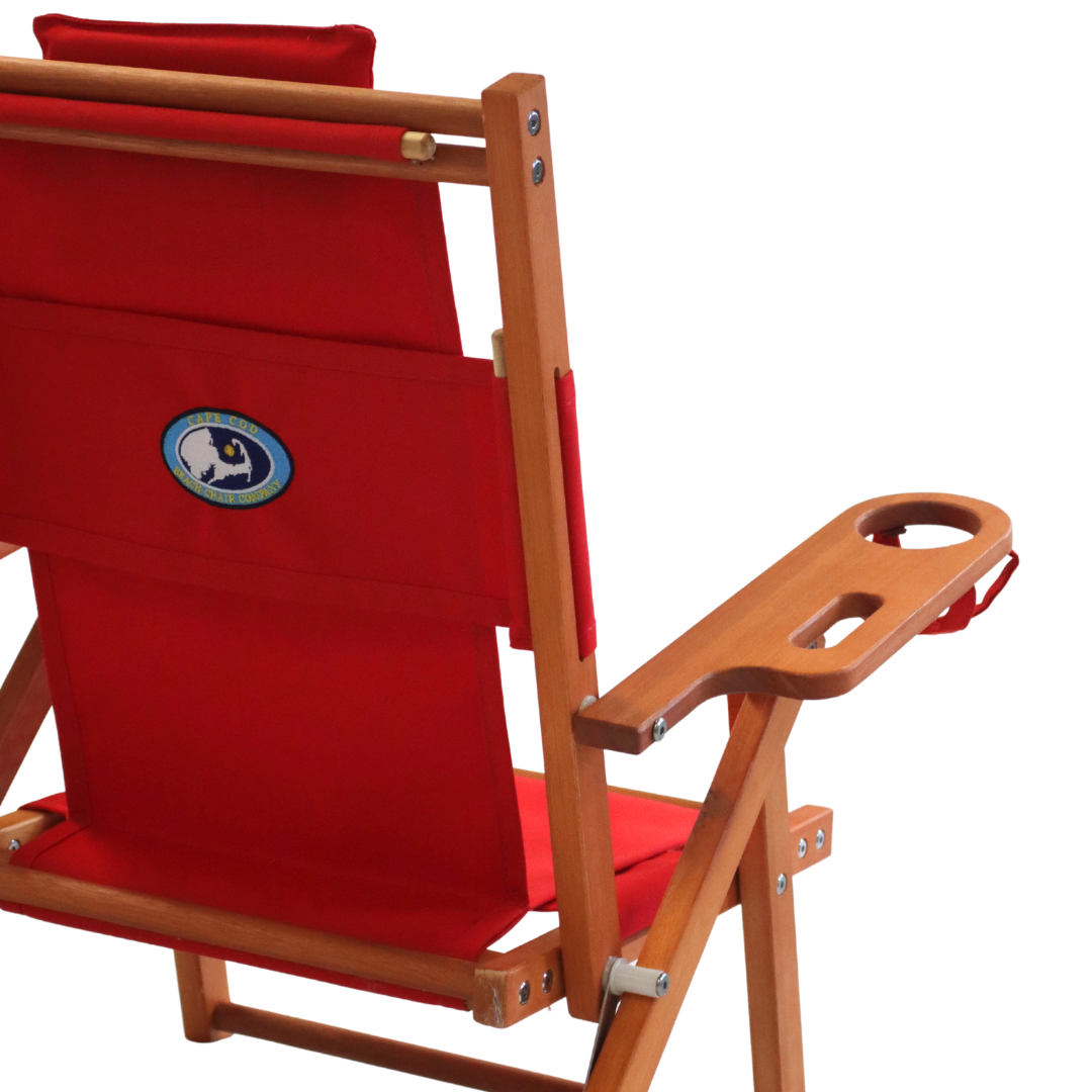 Kid's red folding beach chair with wooden armrest background