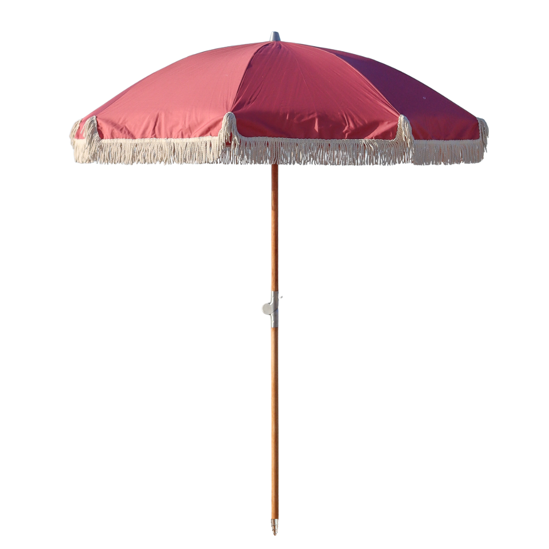 A nantucket red or pink solid colored beach umbrella with wood pole and tassels.