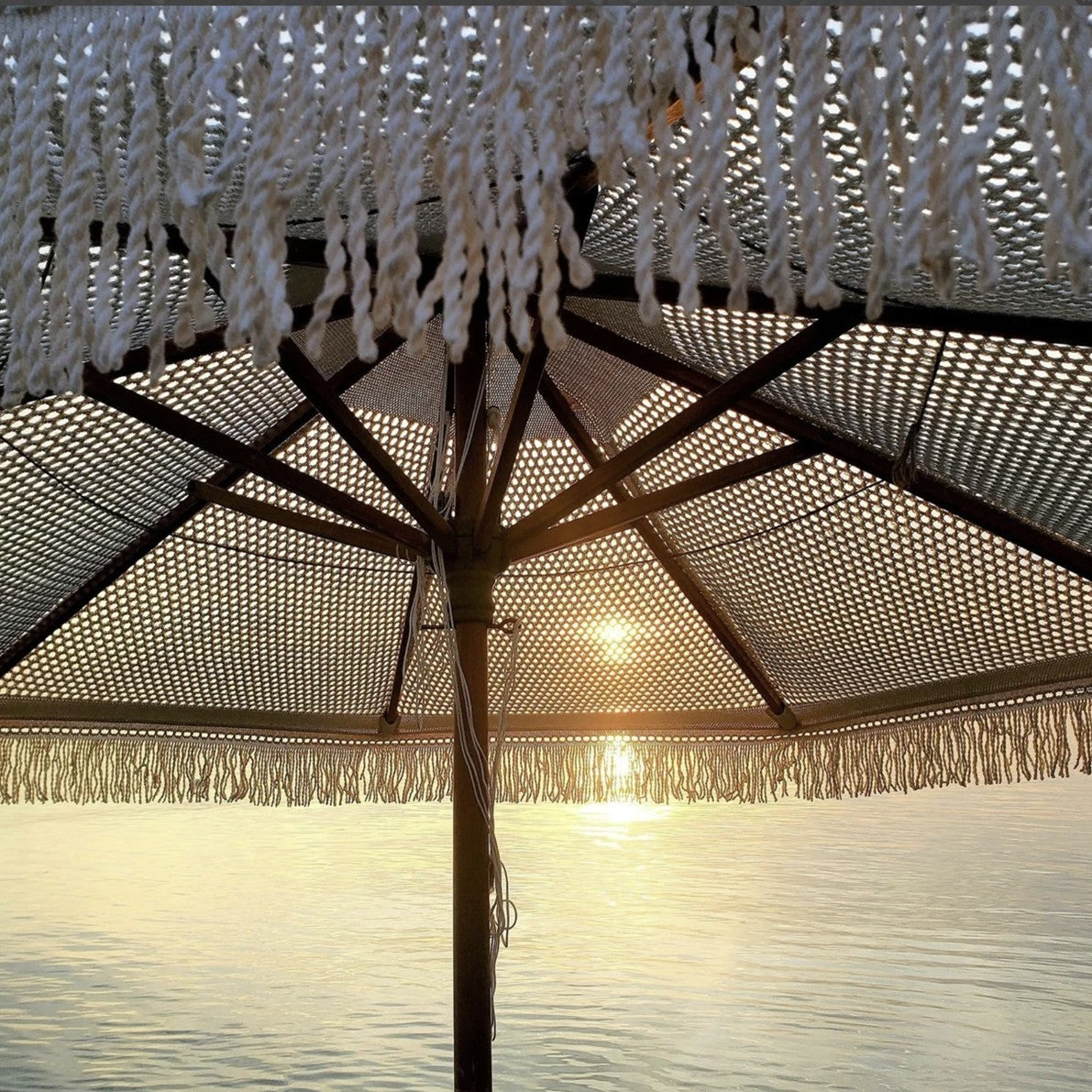 A macrame umbrella against blue sky by the ocean