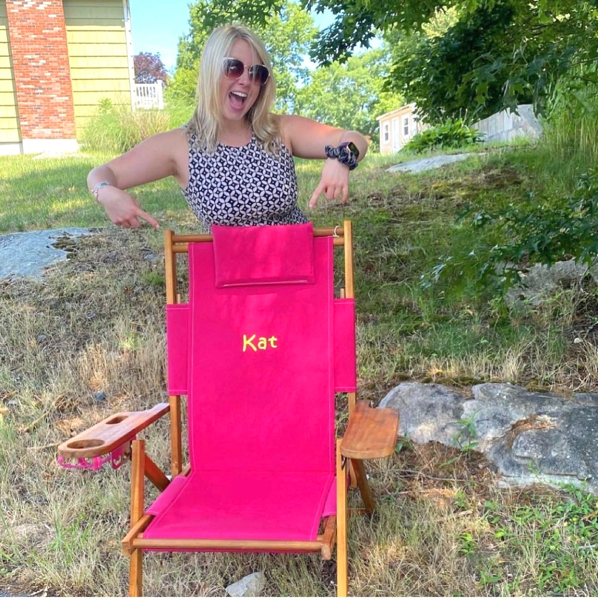 An excited woman receives a pink beach chair with embroidered name as a bachelorette gift.
