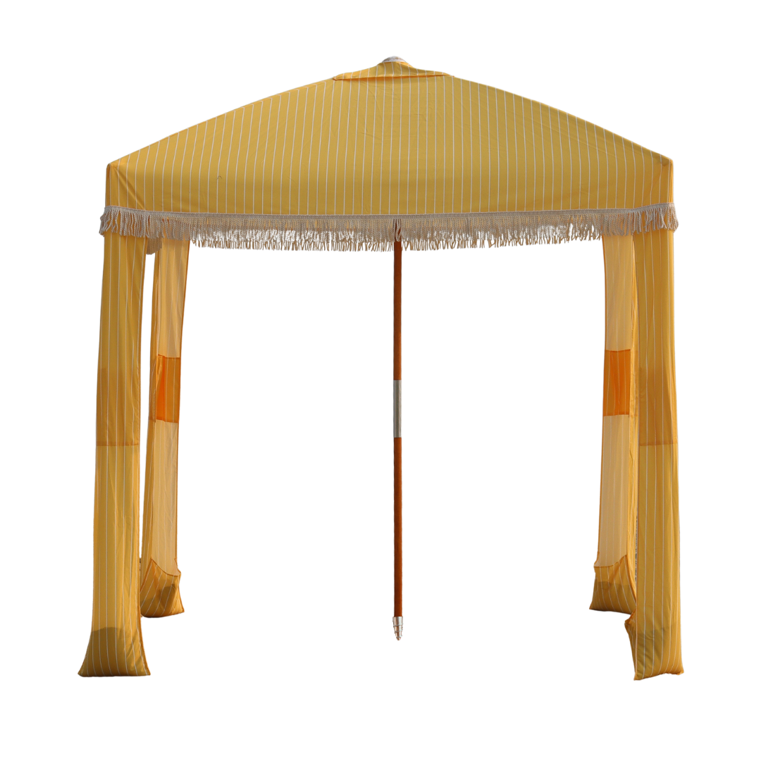 A luxury yellow and white striped portable beach cabana with stylish white tassel fringe.